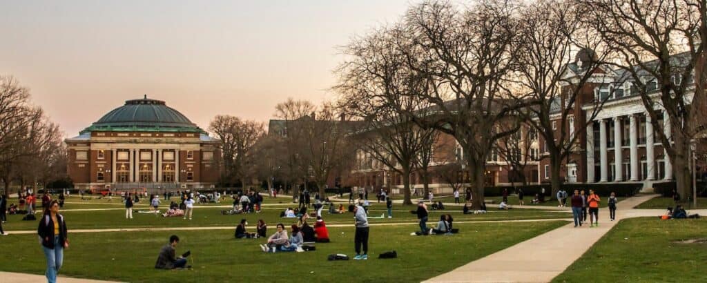 UIUC 校园主广场傍晚景色,学生在草地上休憩,远处为圆顶建筑 Foellinger Auditorium